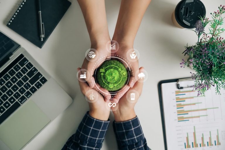 Manos de profesionales sosteniendo un botón verde con íconos, simbolizando la tecnología sostenible en el ámbito empresarial.